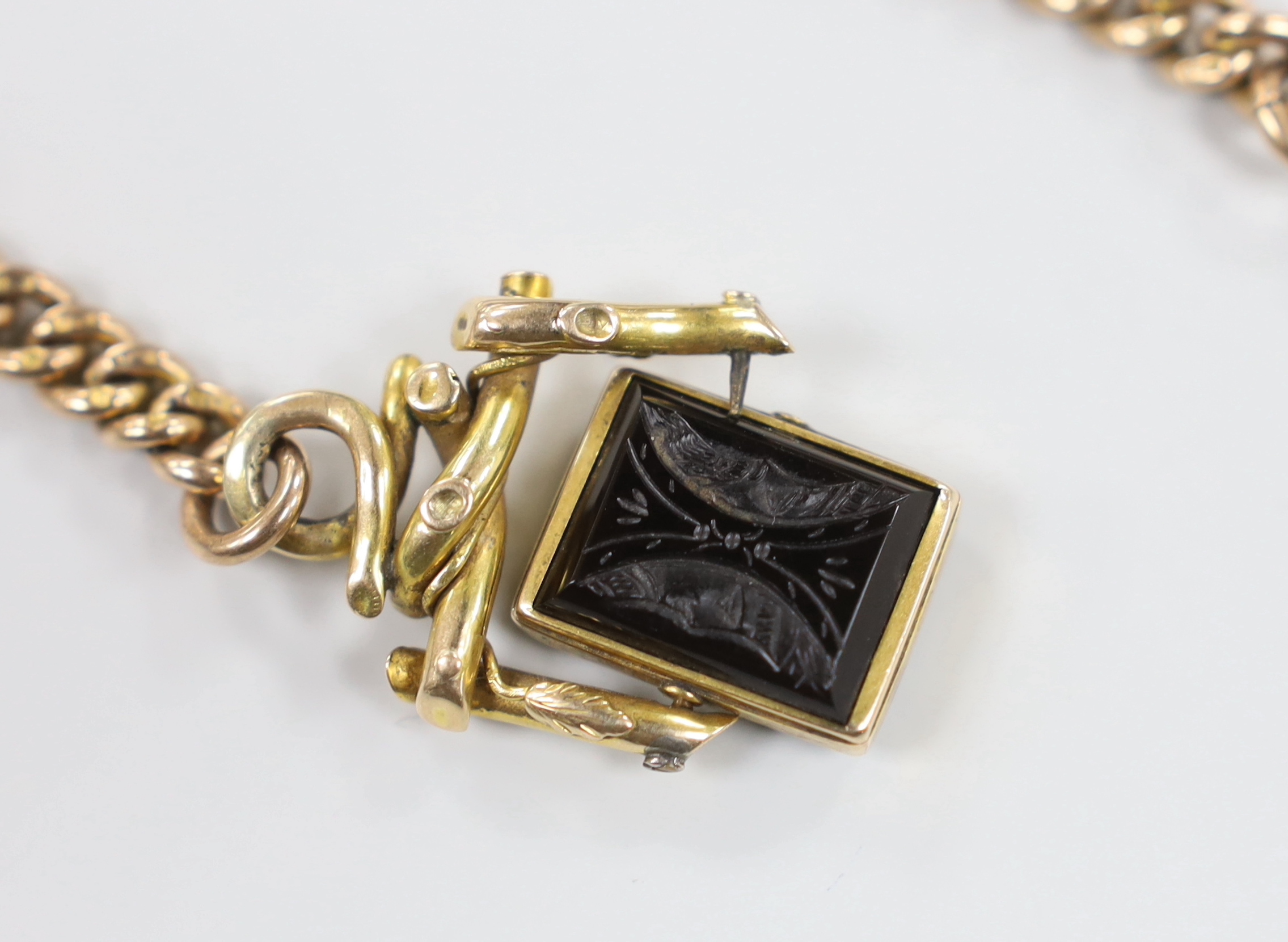 An early 20th century 9ct gold curb link chain, 39cm, hung with an Austro Hungarian yellow metal and chalcedony set spinning fob, gross weight 47.1 grams.